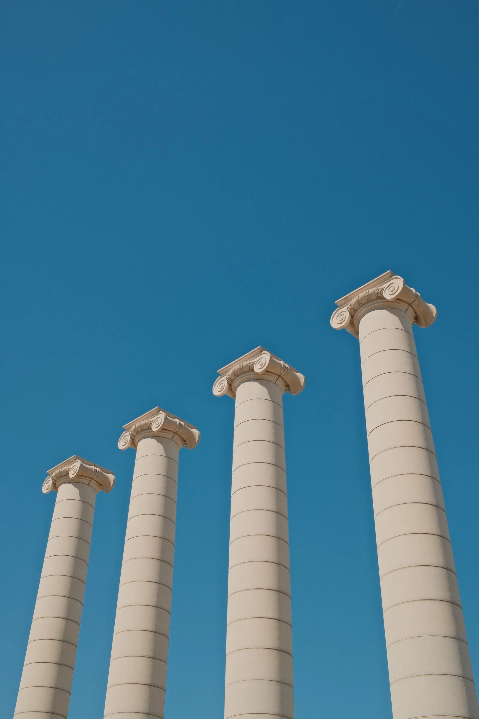 Four white Ionic columns against a clear blue sky